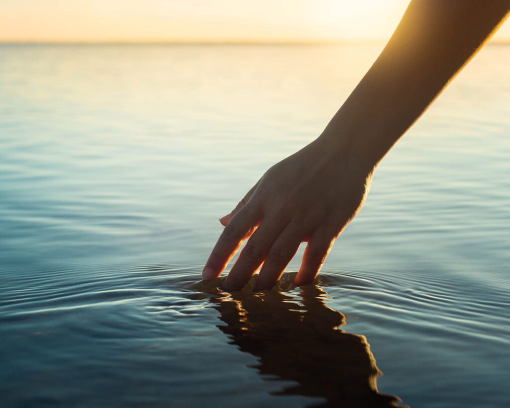 A,Female,Hand,Touching,The,Ocean,Water,In,Front,Of